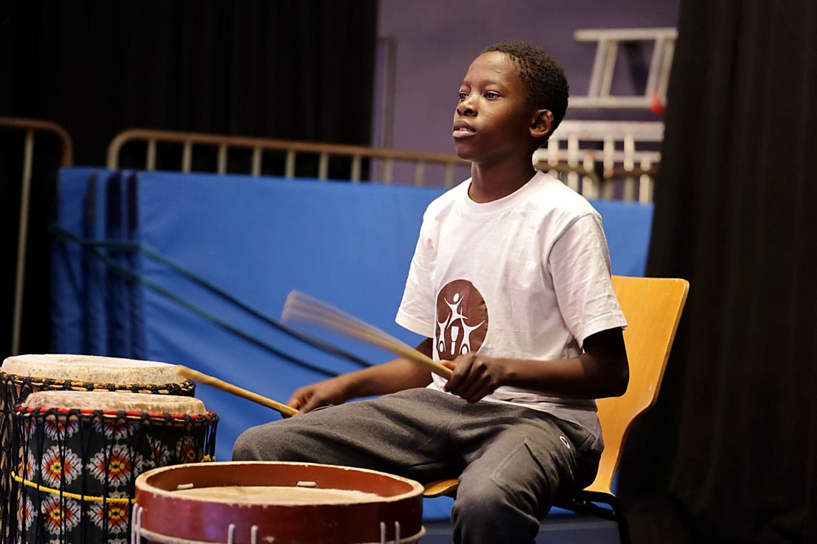 A young Nafsi drummer in the group's kit, mid-beat on stage